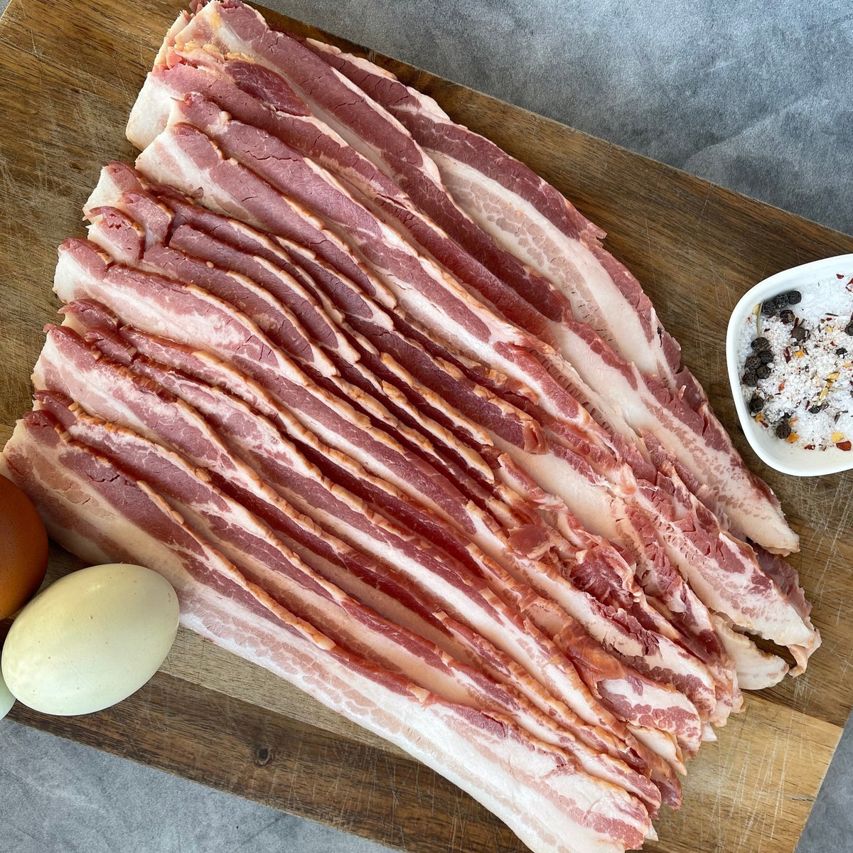 bacon on a cutting board with colorful eggs